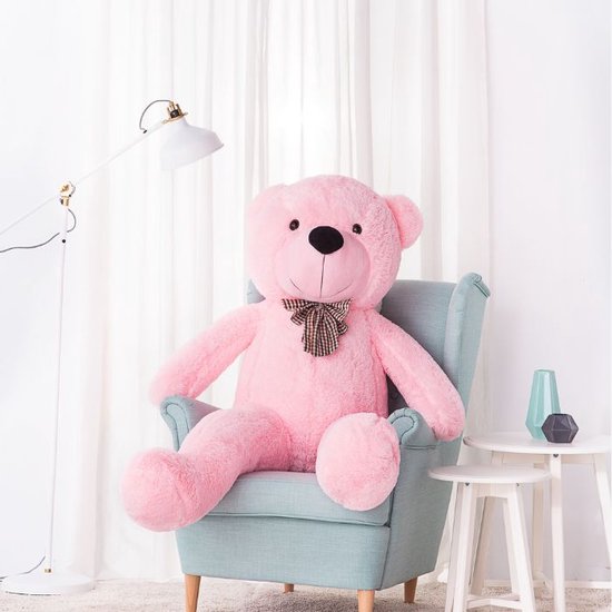Roze XXL teddybeer van 160 cm, zittend in een fauteuil met een ruitjes strik.