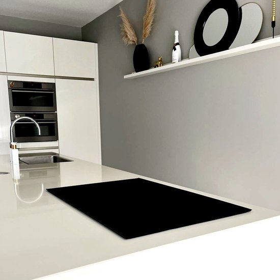 Een zwarte inductiebeschermer op een wit aanrechtblad in een moderne keuken.