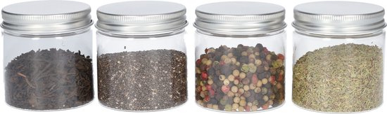 Vier glazen potjes met zilverkleurig schroefdeksel, gevuld met gedroogde thee, chiazaad, peperkorrels en gedroogde kruiden.
