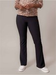 Een zwangere vrouw in een top met luipaardprint en een zwarte flared broek.