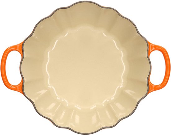 Binnenzijde van oranjerode pompoen braadpan met crèmekleurige binnenkant en golvende rand.
