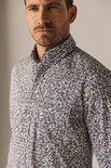 Close-up buste van man met blauw-wit met bruine print overhemd.