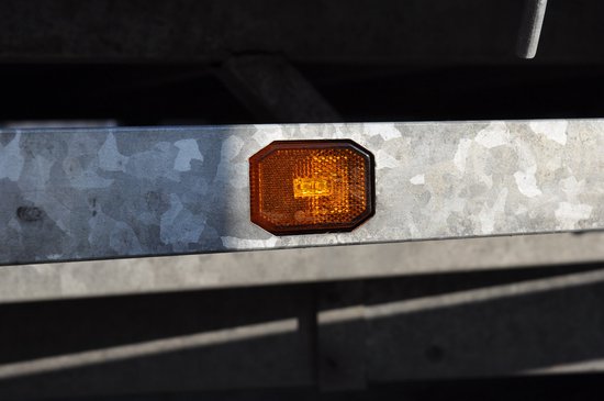 Octogonale oranje LED lamp op een metalen rail.