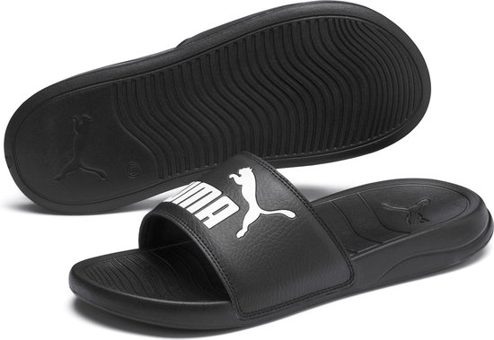 Zwarte Puma slipper met witte opdruk, en de onderkant van een andere slipper.