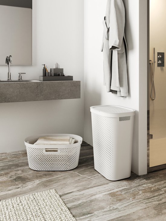 Witte wasmand met deksel en ronde perforaties, naast een bad met douche.
