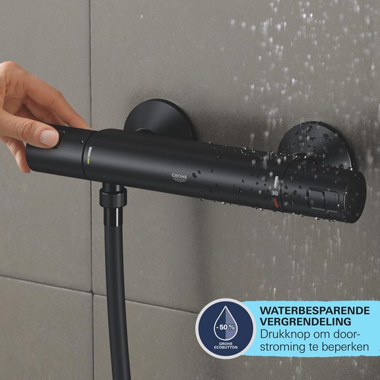 Een hand activeert de waterbesparende "EcoButton" op een zwarte thermostaatkraan. Water druppelt langs de kraan.