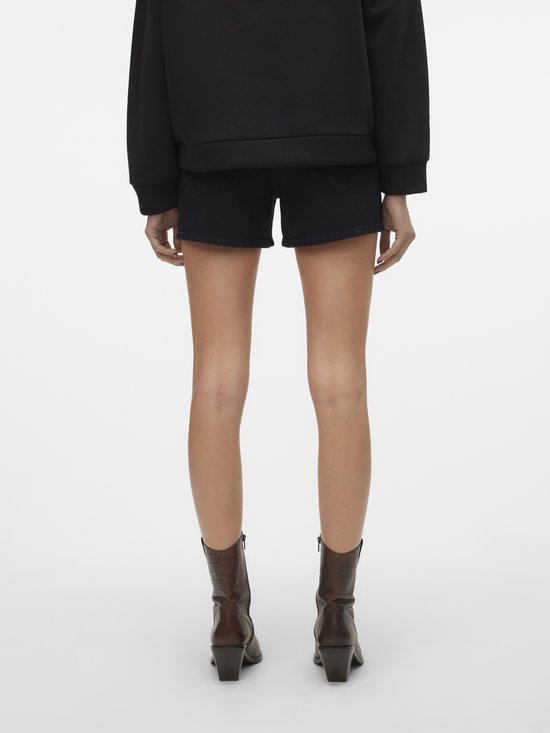 Donkere denim shorts met rafelige zoom, gedragen door een model met bruine laarzen.
