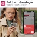 Vrouw kijkt bezorgd naar smartphone met pushmelding van rookmelder alarm. Real time pushmeldingen, altijd en overal op tijd handelen.