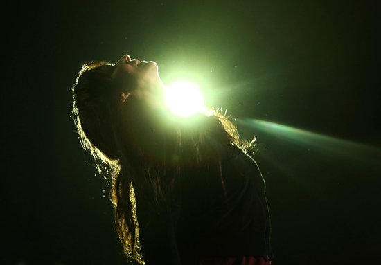 Silhouet van een vrouw met lang haar dat oplicht door een felle lamp.