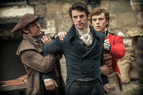 Drie mannen in historische kostuums, een in een blauwe jas, een in een rode jas, worden vastgehouden.