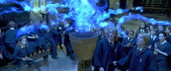 Studenten om een grote kom met blauwe vlammen in een hal.