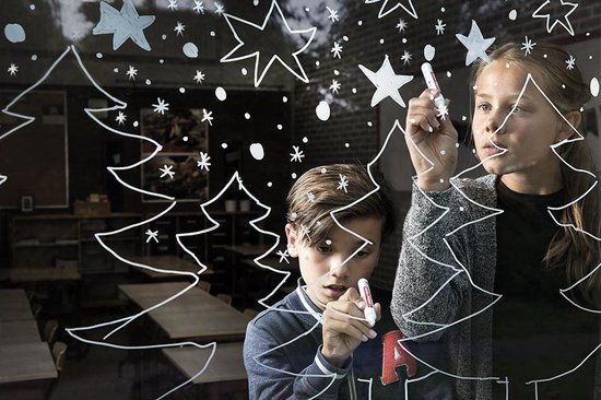 Kinderen tekenen kerstbomen en sneeuwvlokken op een raam.