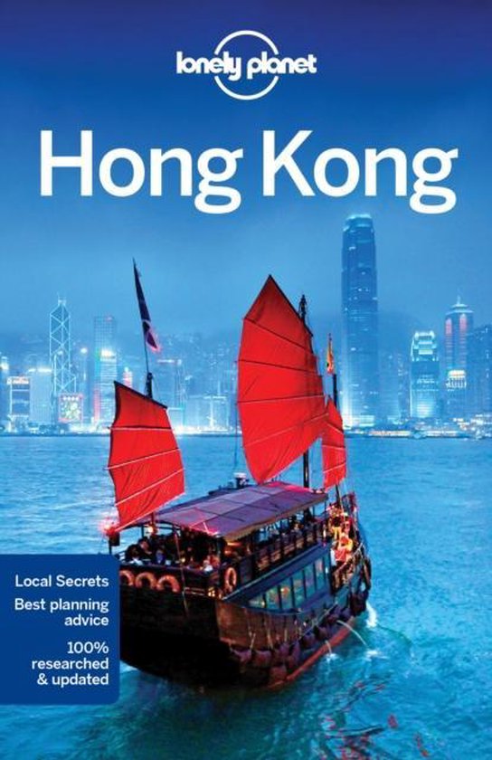 Lonely Planet Hong Kong: Rode zeilboot vaart op water met skyline van Hong Kong op de achtergrond.