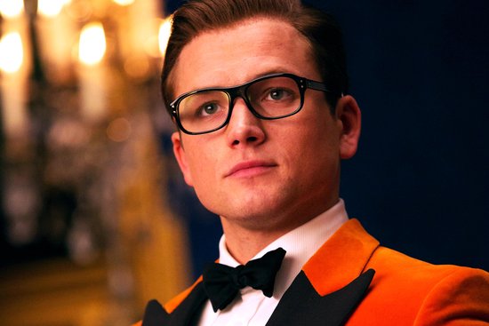 Man met bril, oranje colbert en vlinderdas.