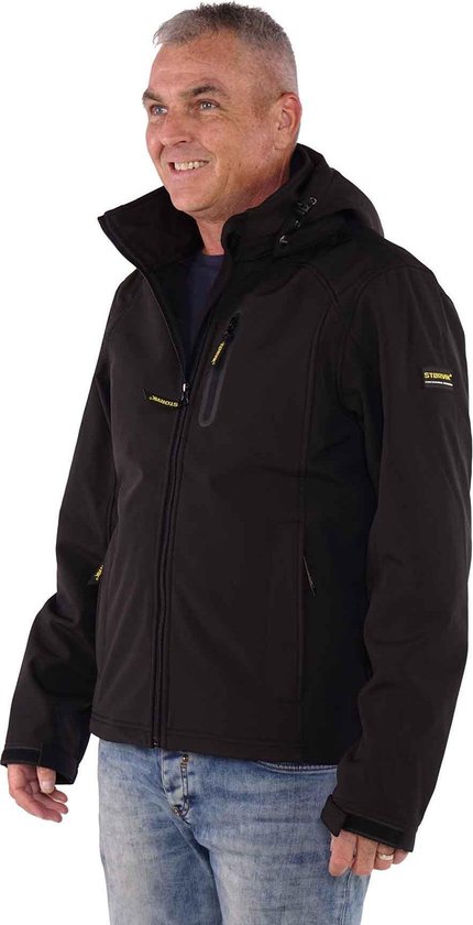 Man met een zwarte softshell jas, spijkerbroek, staand, kijkend naar links.