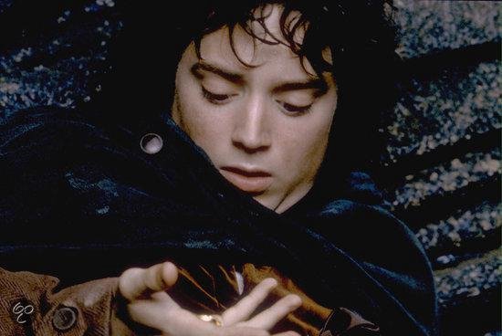 Frodo, met gesloten ogen, houdt de ring in zijn hand en is omhuld door een donkere mantel.