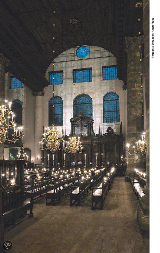Interieur van de Portugese Synagoge in Amsterdam met kaarsen en zitplaatsen.