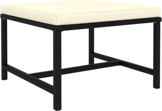 Table basse noire avec coussin crème et un cadre en polyrotin tressé.