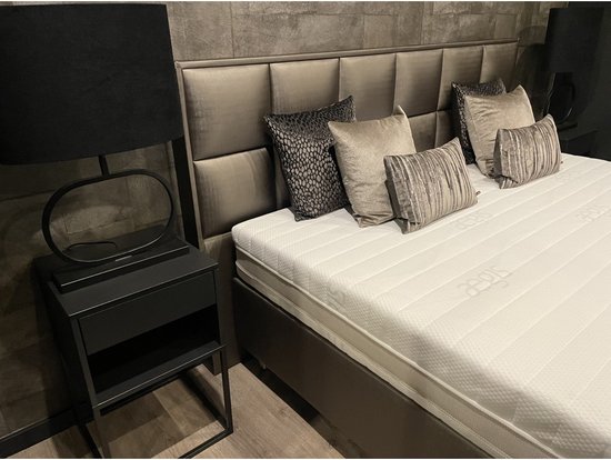 Luxe bed met bruin gestoffeerde boxen, wit matras, grijs gestreept hoofdbord en een faux bont sprei.