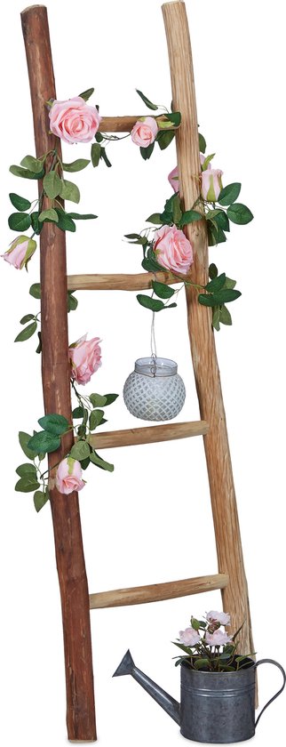 Houten ladder met roze rozenrank en metalen lantaarn, met gieter en bloemen onderaan.
