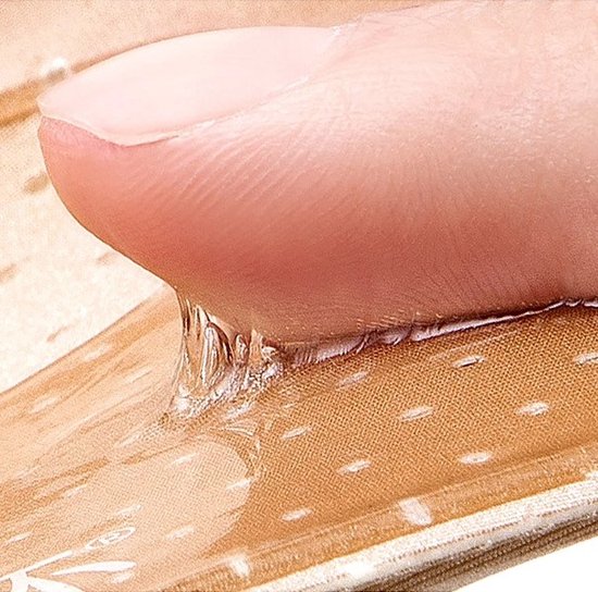 Close-up van een duim die op de kleeflaag van een beige plakbeha drukt, met druppels.