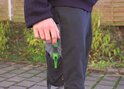 Mannelijke hand met groene markeerstift in het werkbroekvak. Zwarte en grijze werkbroek.