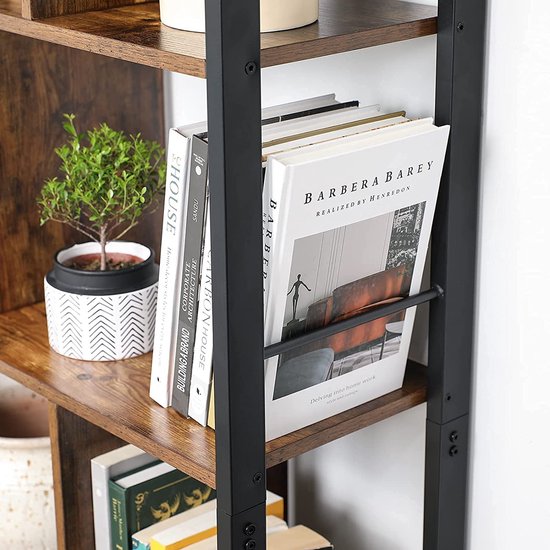 Dichtbij van een boekenplank met boeken, een plantje in een witte pot met zwarte zigzaggroeven en een stapel boeken met een metalen houder.