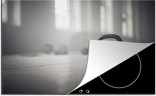 KitchenYeah® Inductie beschermer 76x51.5 cm - Verschillende kettlebellgewichten op de vloer in een fitnessruimte - Kookplaataccessoires - Afdekplaat voor kookplaat - Inductiebeschermer - Inductiemat - Inductieplaat mat