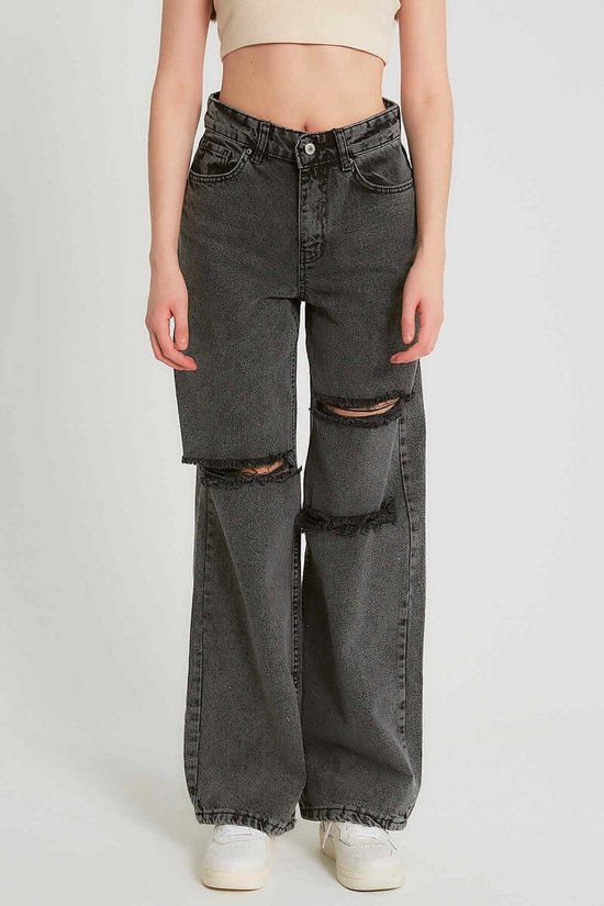 Model in wijde, grijze jeans met ripped knieën en hoge taille.