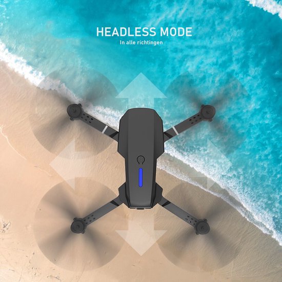 Zwarte drone met draaiende propellers boven strand en zee. "Headless Mode" in alle richtingen.