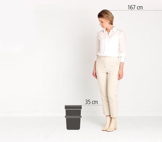 Une femme de 167 cm se tient à côté de deux poubelles Brabantia gris foncé empilées de 35 cm de haut.