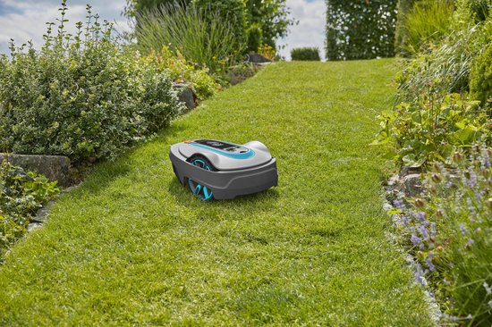 Grijze robotmaaier met blauwe en oranje accenten op een schuin grasveld.