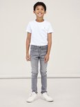 Jongetje in een witte T-shirt en strakke, grijze jeans.