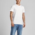 Man in een wit T-shirt en blauwe spijkerbroek, staand naar de zijkant gedraaid.