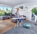 Vrouw strijkt op strijkplank met bloemenprint (roze, blauw, wit).