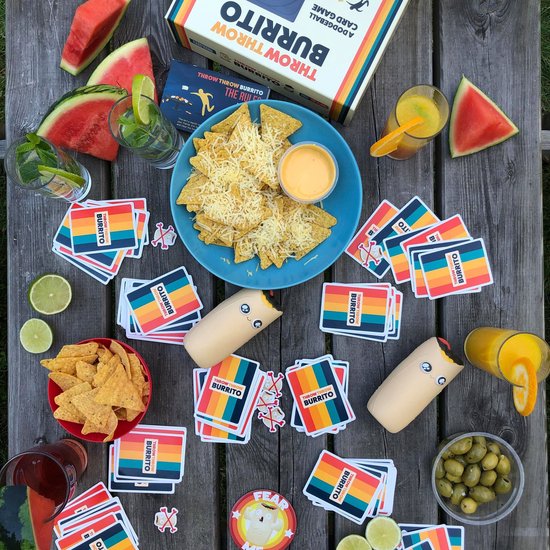 Tafel vol met Throw Throw Burrito kaarten, nacho's, salsa, olijven en drankjes.