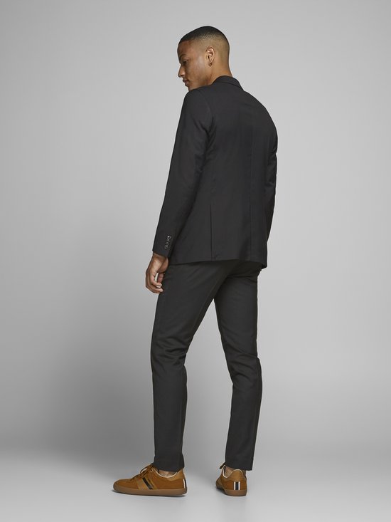 Jonge man draagt een zwarte Jack & Jones blazer met een witte T-shirt en zwarte broek, van achteren gezien.