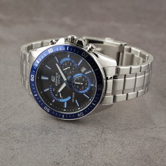 Zilverkleurig Edifice Casio horloge met blauwe lunette en zwarte wijzerplaat op grijze ondergrond.