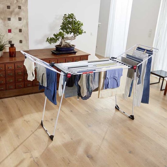 Étendage Vileda blanc avec divers vêtements, y compris des pantalons et des serviettes.