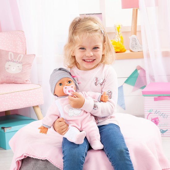 Meisje met babypop in roze slaappakje en grijze muts.