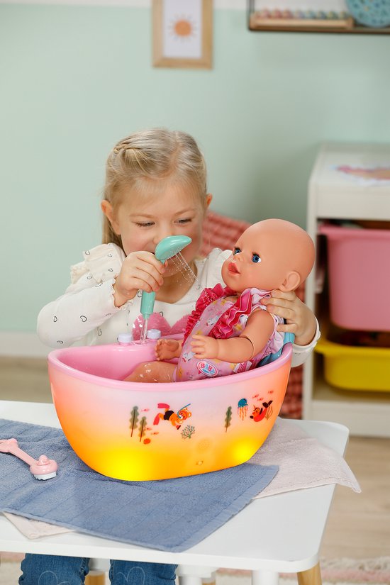 Meisje met hartjes trui laat een pop in een roze, verlicht badje met douche spelen.