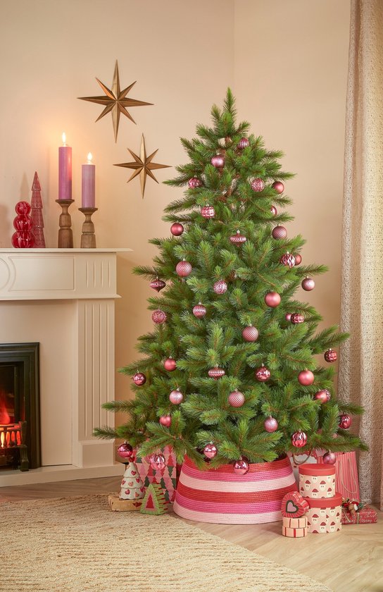 Een versierde kerstboom met roze kerstballen, bijpassende geschenkdozen en een roze-wit gestreepte boomrok.