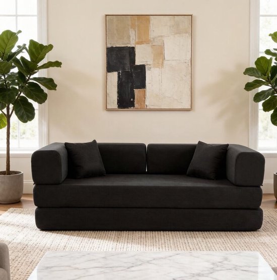 Zwarte corduroy slaapbank, 200cm x 100cm, met twee kussens, in een woonkamer.