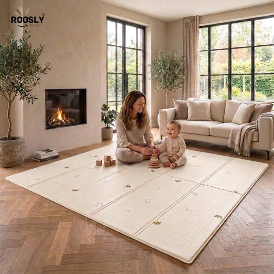 Beige speelmat van 180 x 200 cm met subtiele gouden kronen. Een baby en moeder zitten erop in een woonkamer.
