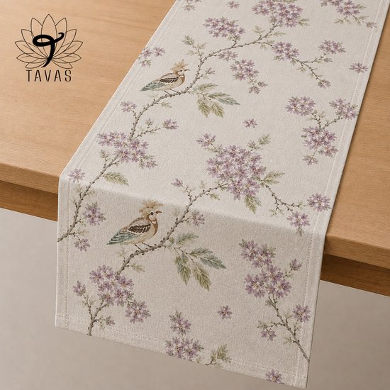Chemin de table crème avec un oiseau sur une branche avec des fleurs violettes et des feuilles vertes. Tissu panama en coton.
