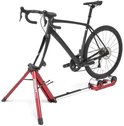 Een zwarte racefiets op een rode Fietstrainer met het merk Feedback Sports.