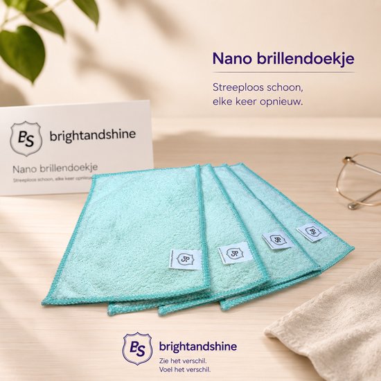 Vier lichtgroene, zachte brillendoekjes met turkooizen randen liggen op een houten tafel. Boven de doekjes staat 'Nano brillendoekje'.
