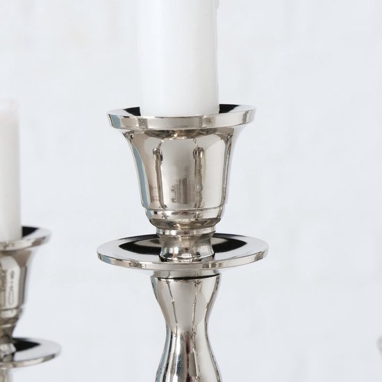Close-up van een zilverkleurige kaarsenhouder op een kandelaar, met witte kaars.