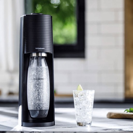Zwarte SodaStream Terra met bruisende fles en glas met limoen.