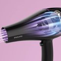 Zwarte Philips föhn met glanzende afwerking en paarse accenten. Zichtbare luchtstroom met blauw en paars licht.